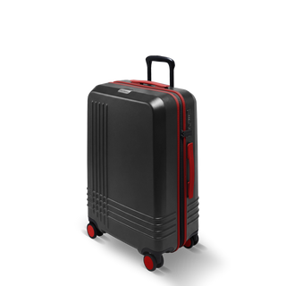 ROAM Matte Edit hardside check-in suitcase in matte black with red trim, three-quarter view